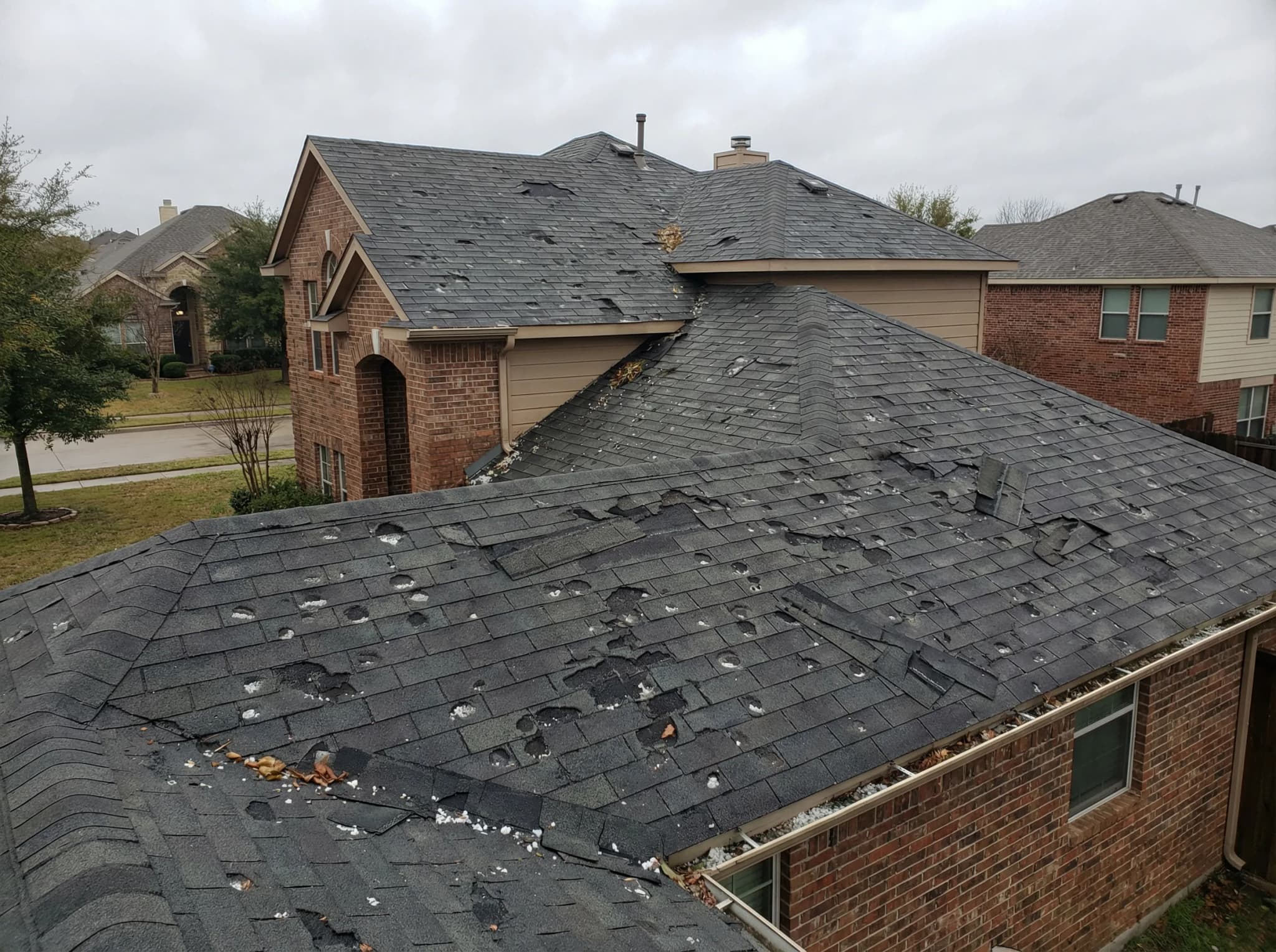 Hail-damaged residential roof in DFW with cracked and missing shingles